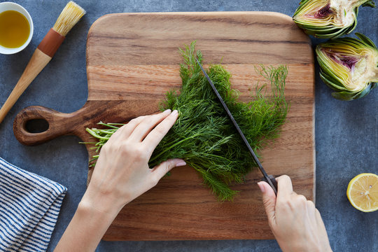 Anonymous woman's hands chopping herbs on a cutting board