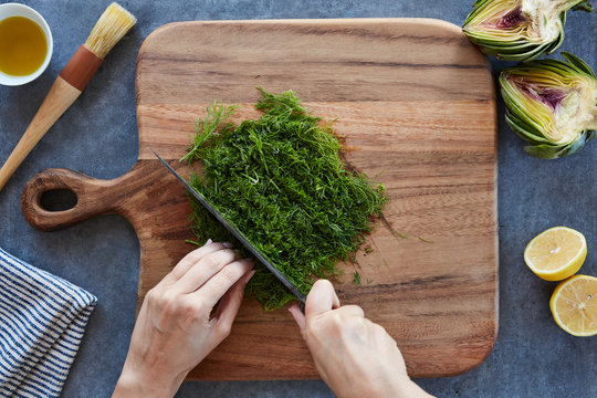 Anonymous woman's hands cutting herbs with a sharp knife