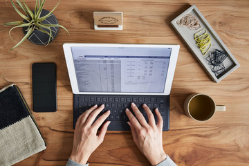 Overhead shot of a small business owner typing on a tablet computer
