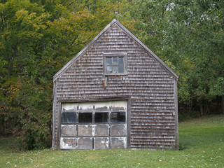 Old garage surrounded by trees and green grass