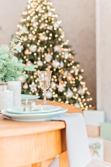 Christmas wooden table, a glass of champagne and christmas tree, table setting