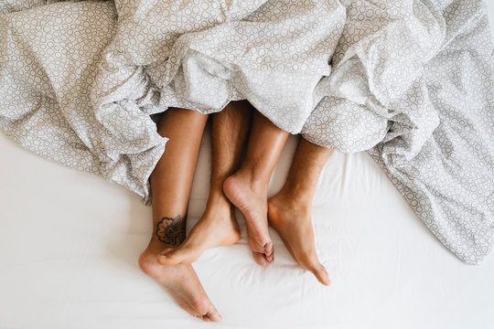 Detail of the feet of a couple lying in bed