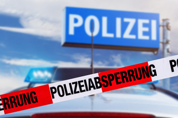 Polizeiabsperrung mit Polizeiauto im Hintergrund