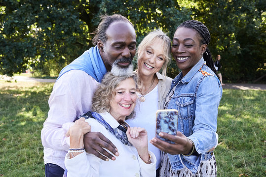 Happy faces group selfie at park.