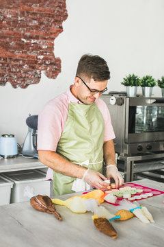 Man filling fresh baked macrons