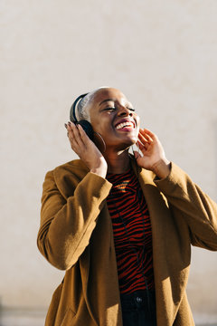 Cheerful black woman listening to music on street