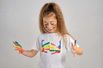 Little girl in white painted t-shirt is posing standing isolated on white and gesticulating with...