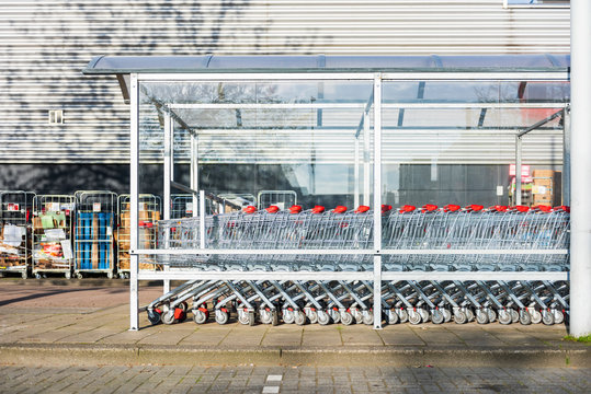 Row of supermarket shopping trolleys under awning on pavement