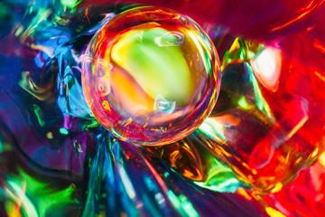 Abstract shot of glass ball on colorful holographic backdrop