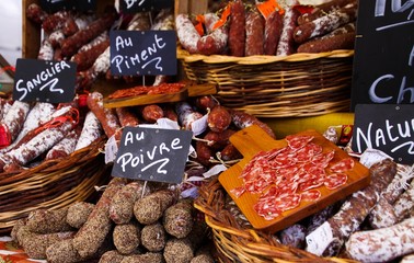 Different kinds of French salami provencale presented in wicker baskets with handwritten chalk...