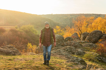 Naklejka premium Old gray-haired tourist with a beard on the background of the gorge and stones