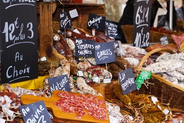 Different kinds of French salami provencale presented in wicker baskets with handwritten chalk...