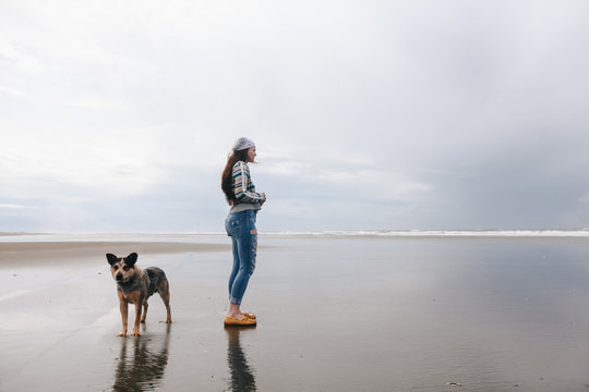 young woman walks on beach with dog