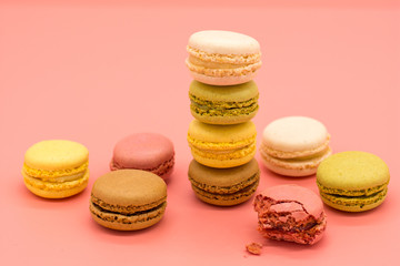 delicious macarons full and bitten and crumbs arranged on pink background