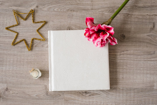 White wedding photo album on wooden background with flower and Christmas star, top view