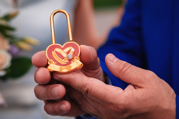 Hand holding a heart shaped lock and key on a red background