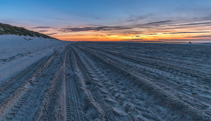 Abendrot am Strand von Renesse in den Niederlande. Der Sand vom Strand aufgewühlt von Reifen.