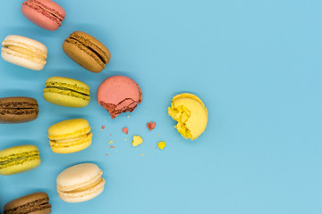 Delicious macarons full and bitten and crumbs arranged on colorful background top view 