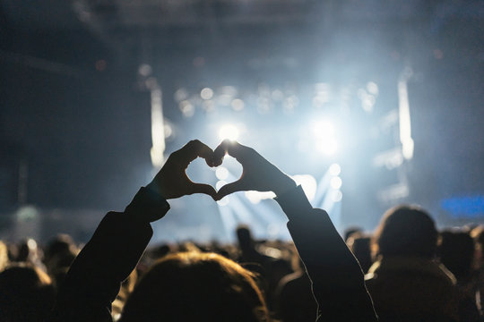 Silhouettes of concert crowd in front of bright stage lights