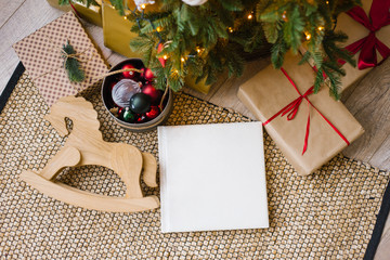 Photo book in white leather cover, wedding or family photo album under the Christmas tree surrounded by Christmas gifts