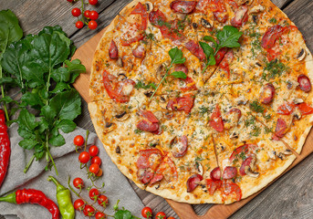 baked round pizza with smoked sausages, mushrooms, tomatoes, cheese and arugula leaves