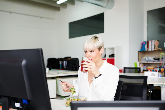 Modern businesswoman enjoying meal in office