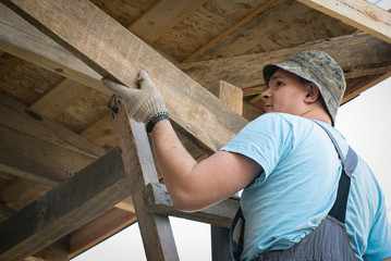 Worker is building a roof of house.