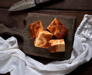 baked square pieces of pumpkin cheesecake on a wooden board