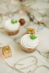 New Year's sweets on a marble table. Christmas cupcakes decorated with mastic and cream