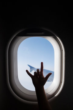 Silhouette of girl's hand gesturing by airplane window