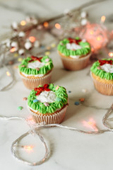 New Year's sweets on a marble table. Christmas cupcakes decorated with mastic and cream