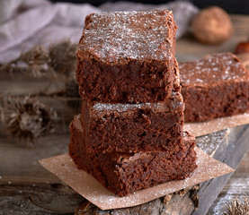stack of baked square pieces of brownie pie on a wooden board