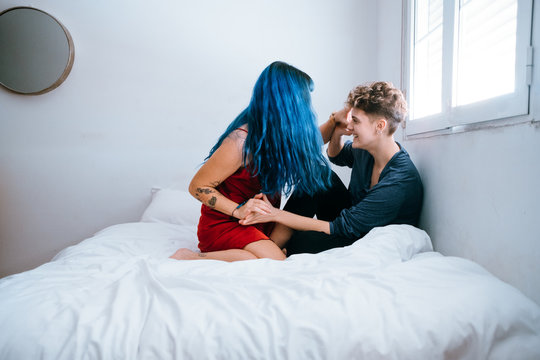 Lesbian couple playing and kissing on their bed in the morning