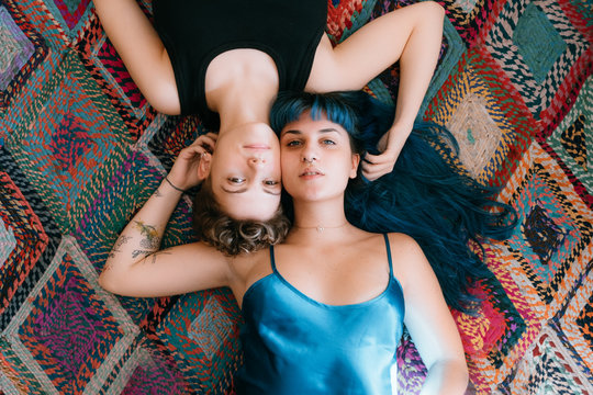 two lesbian girls lying on a colorful carpet