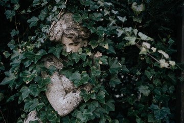 Stone statue of woman hidden in foliage