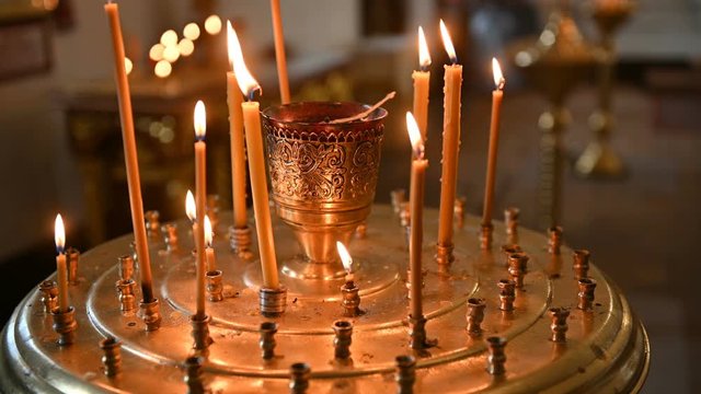 burning candles on a candlestick at the empty orthodox church