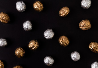 Painted golden and silver walnuts on black background