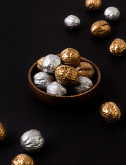 Obraz premium Painted golden and silver walnuts on wooden plate on black background