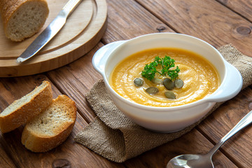 Pumpkin cream soup with croutons on a brown background
