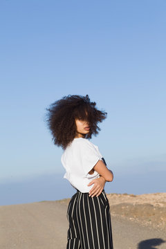 young woman with curly hair in barren landscape