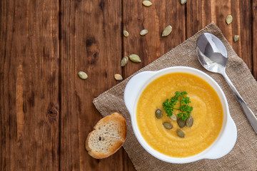 Pumpkin cream soup with croutons and seeds on a wooden dark background