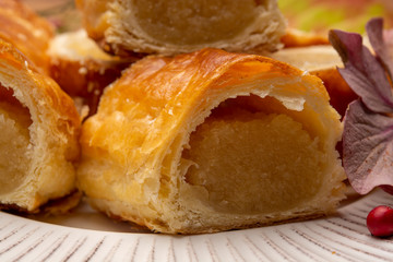 Fresh baked Dutch filled spicy cookies from puff pastry with almonds in autumn colors on dark wooden background