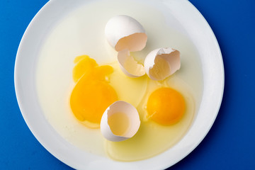 a broken white egg in the plate to prepare some food dishes