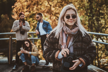 Young positive woman in sunglasses has a nice walk in bright autumn day.