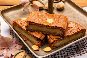 Fresh baked Dutch filled spicy cookies with almonds in autumn colors on dark wooden background