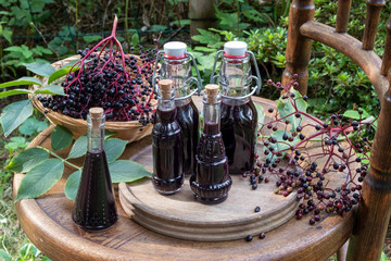 Bottles of black elder syrup with fresh elderberries