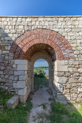 Ancient gate in sun towards a river