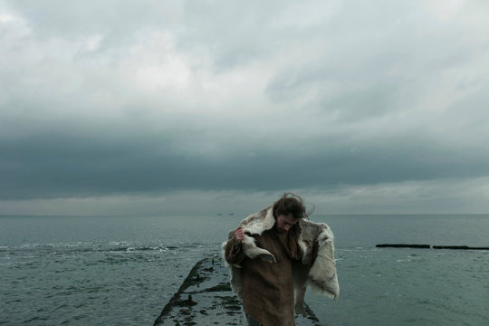 portrait of a guy in animal skin and burlap against the background of the sea and sky