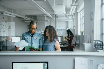 View through window of coworkers reading documents in office