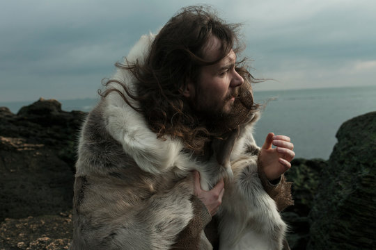 a man in the skin of an animal on the background of the sea